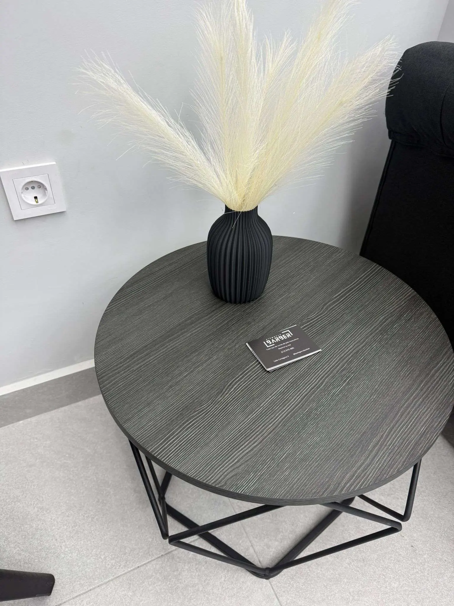 Mesa de espera con decoración moderna en barbería Elegance Barber Ayamonte